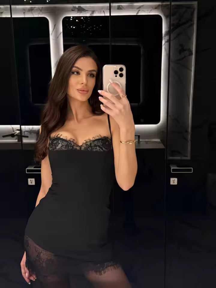 Mirror selfie in a black lace-trim slip dress with sheer tights, in a dark marble bathroom