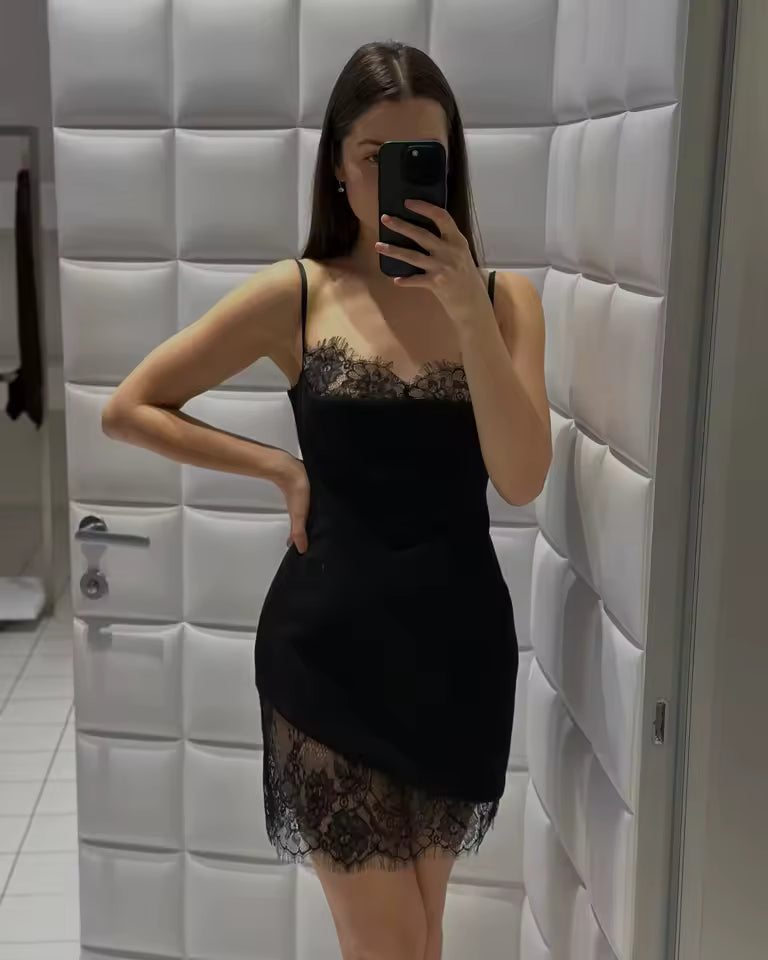 Fitting-room selfie in a black slip dress with lace neckline and an asymmetric lace hem