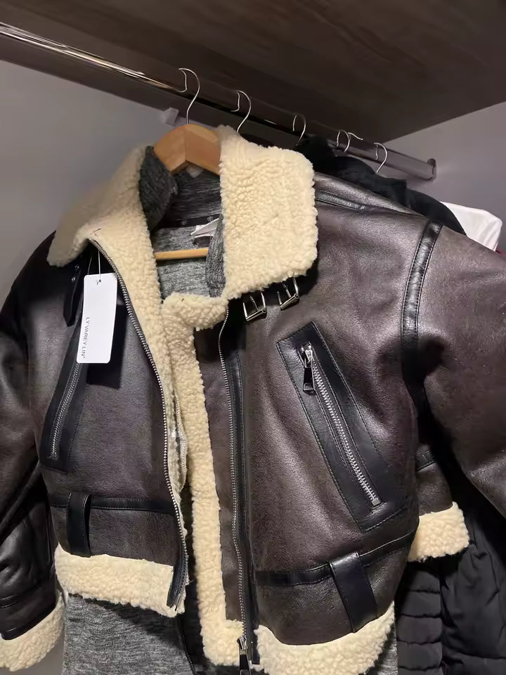 Brown shearling aviator jacket hanging on a rail with its tag still attached