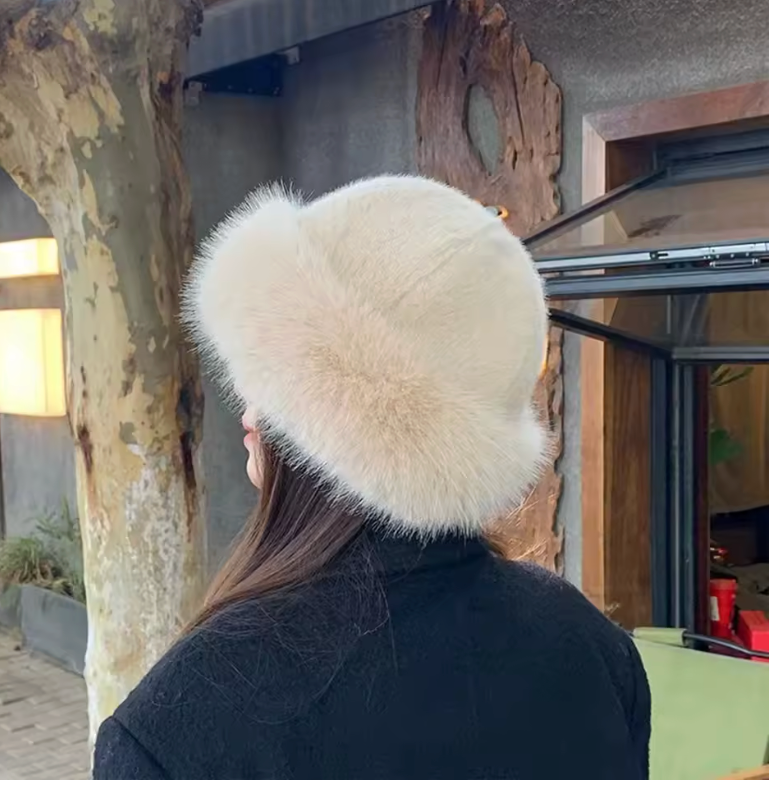 Cream faux fur bucket hat seen from behind, worn with a black textured coat in a courtyard