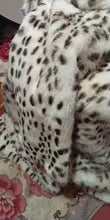 Very small, blurred crop of white and brown spotted faux fur fabric