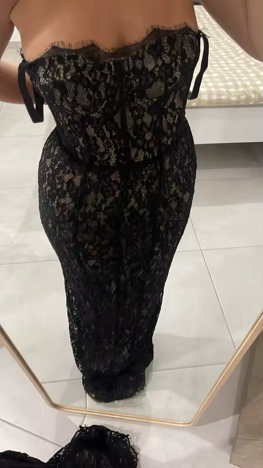Back view of a strapless black lace dress with scalloped trim, in a fitting-room mirror