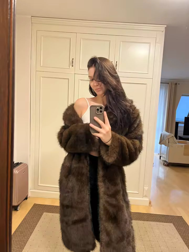 Customer's mirror selfie in a long chocolate-brown faux fur coat over a white top at home