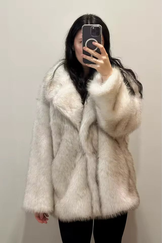 Ivory faux-fur coat with wide notched lapels worn over black trousers, plain-wall mirror selfie