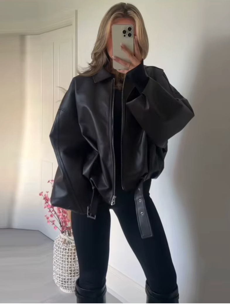 Mirror selfie in an oversized black leather jacket with black jeans and tall black boots
