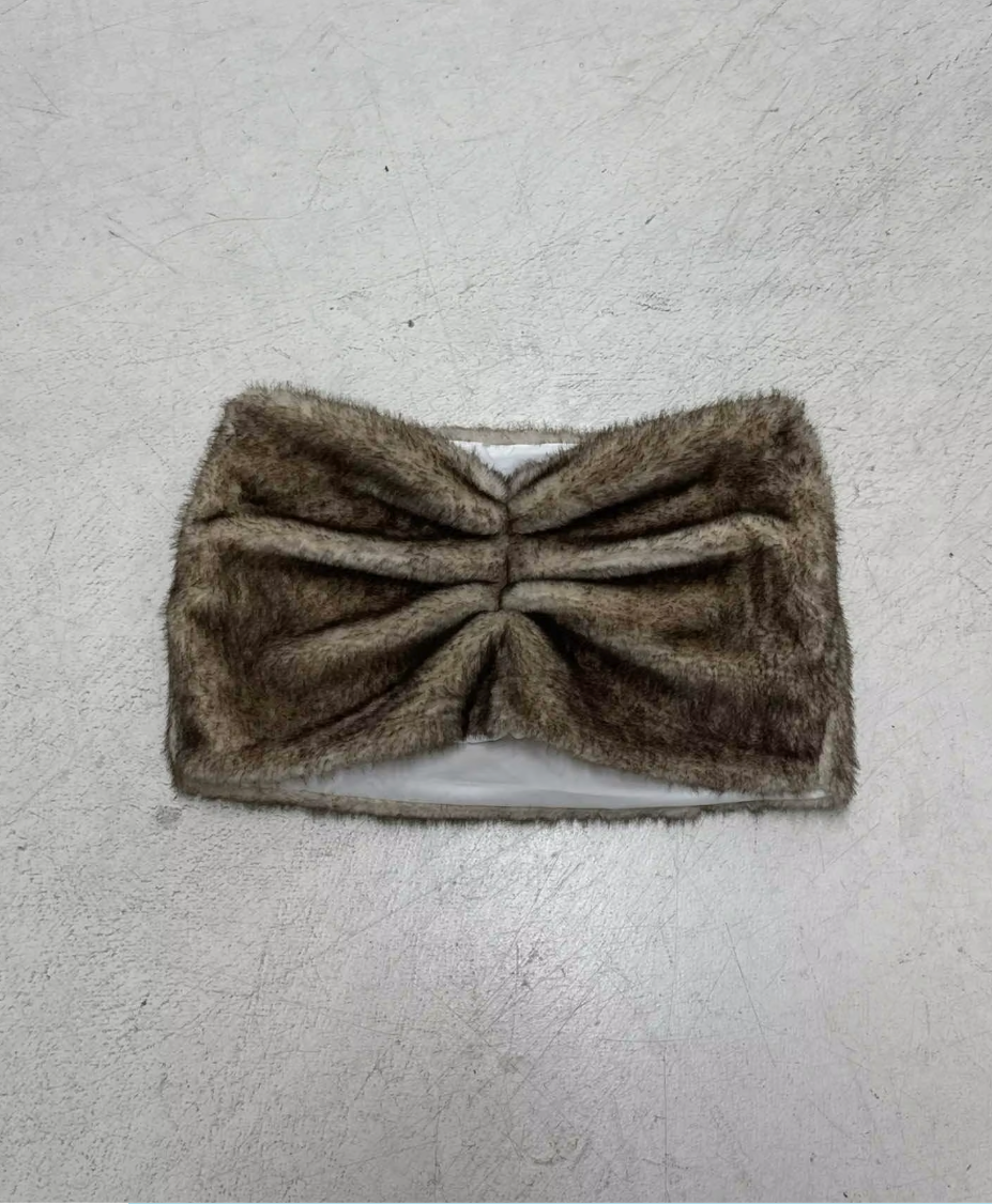 Brown faux fur bandeau top laid flat on a scuffed grey concrete floor