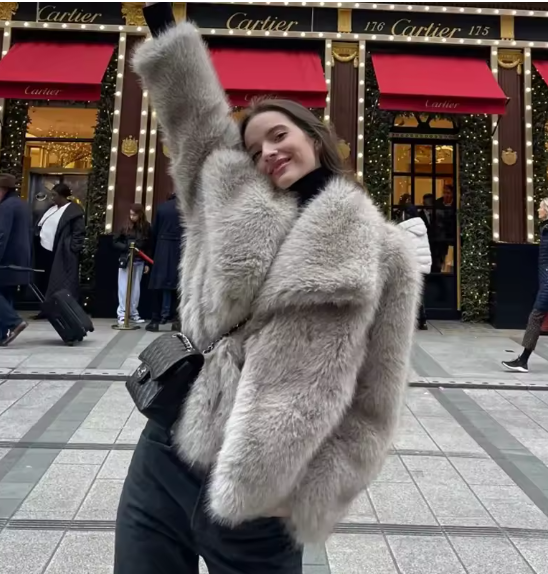 Belted silver-grey faux fur jacket and black trousers outside a lit luxury jewellery storefront