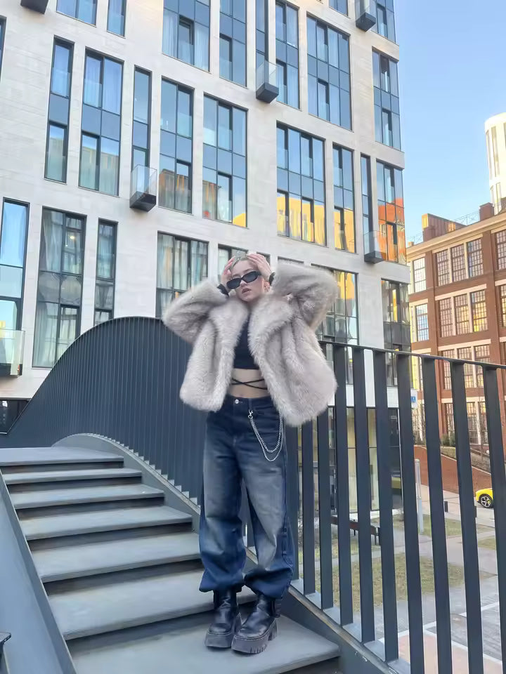A customer in a cropped blush faux-fur jacket, black crop top and wide-leg jeans on city steps