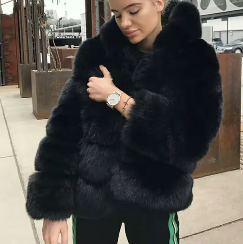 Black faux fur cropped jacket with wide sleeves, worn with striped track pants on a city sidewalk