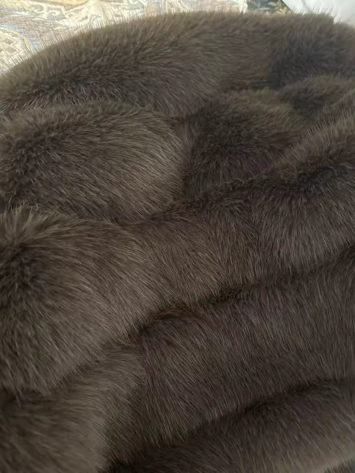 Close-up of dense brown faux fur showing the horizontal panel seams and long guard hairs