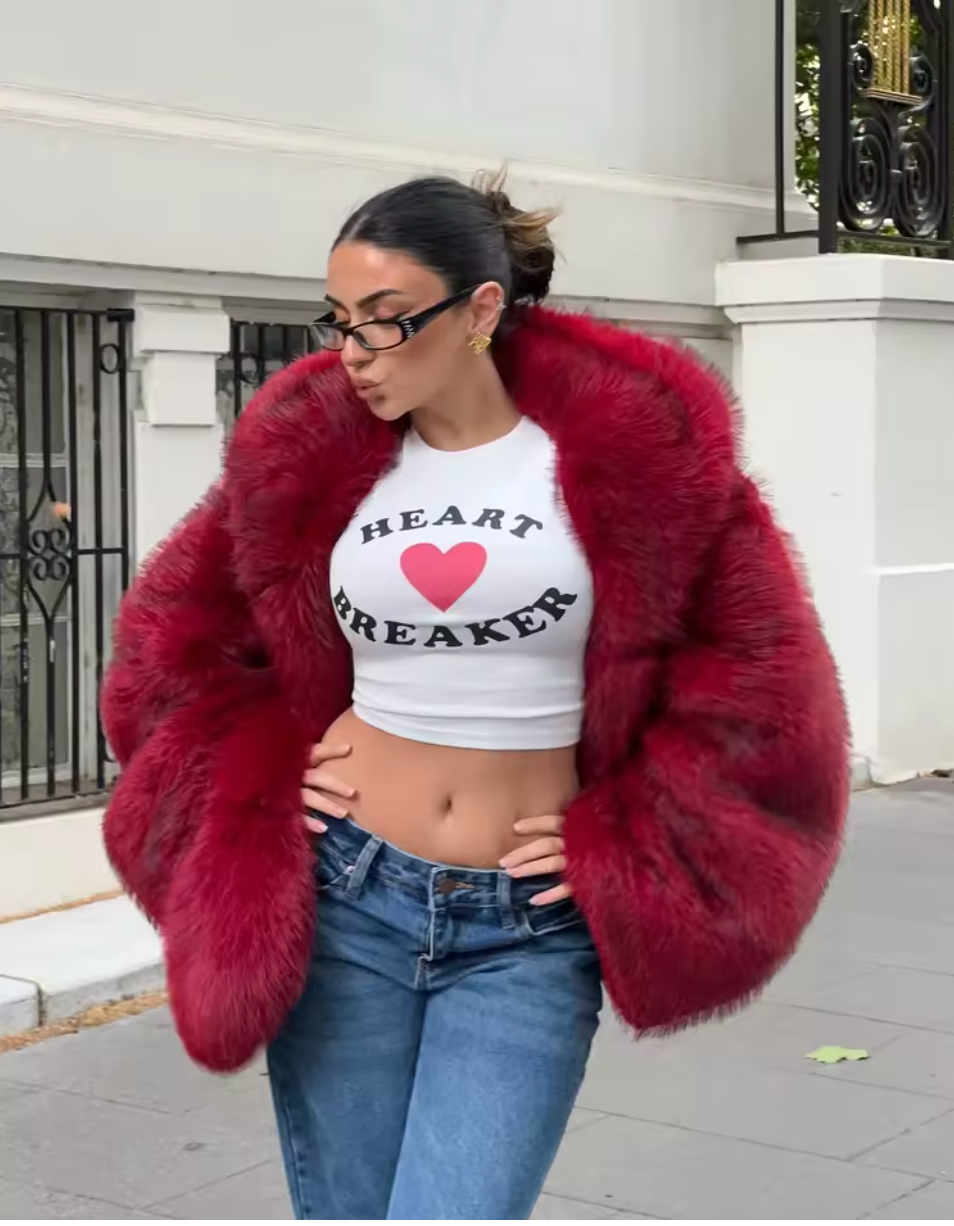 Cropped red faux fur jacket over a white slogan tee and jeans on a city street