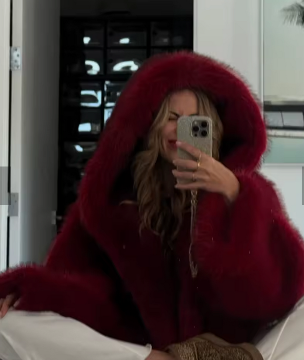 Mirror selfie in a deep red hooded faux fur jacket with the hood pulled up