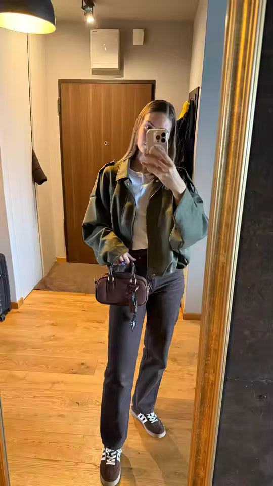 Olive jacket with a white tee, brown trousers and a small brown bag, hallway mirror shot