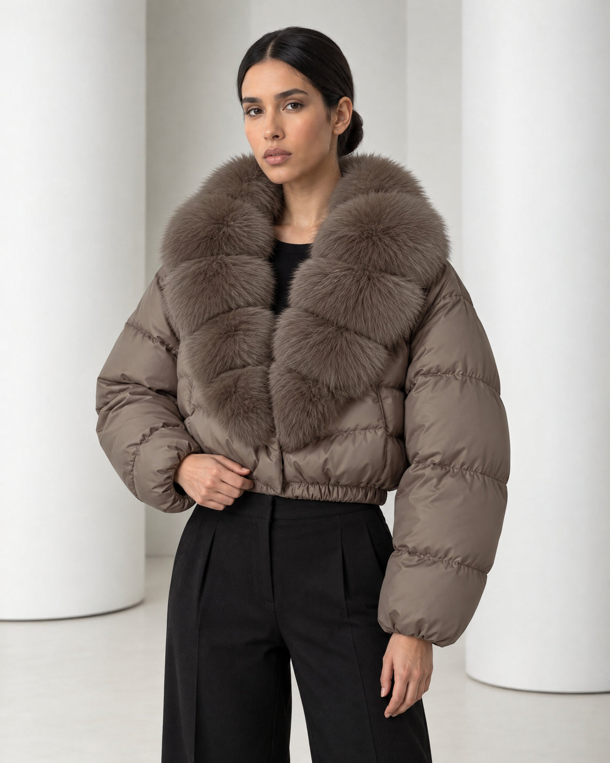 Close view of the Saga taupe puffer, its tiered faux-fur collar, horizontal quilting and gathered elastic waist hem