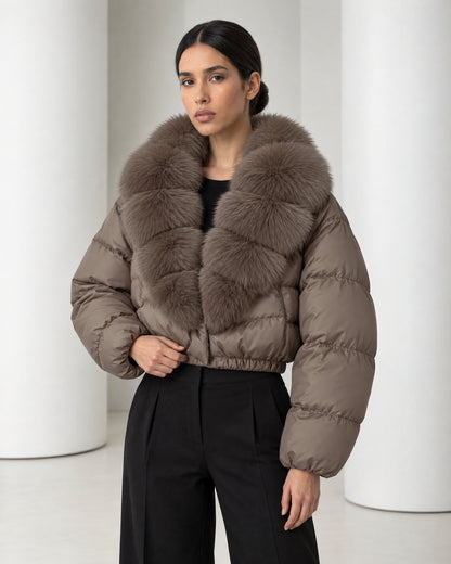 Close view of the Saga taupe puffer, its tiered faux-fur collar, horizontal quilting and gathered elastic waist hem