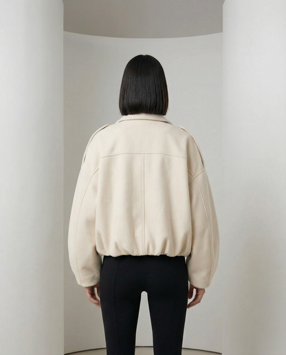 Beige bomber from behind showing the yoke seam and elasticated hem, back view cropped at the hip
