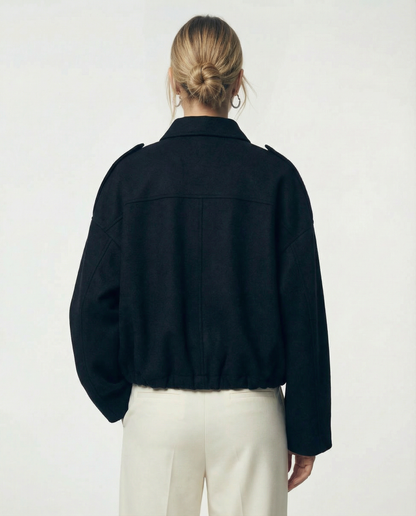 Black cropped bomber from behind, wide drop shoulders and elasticated hem over cream trousers