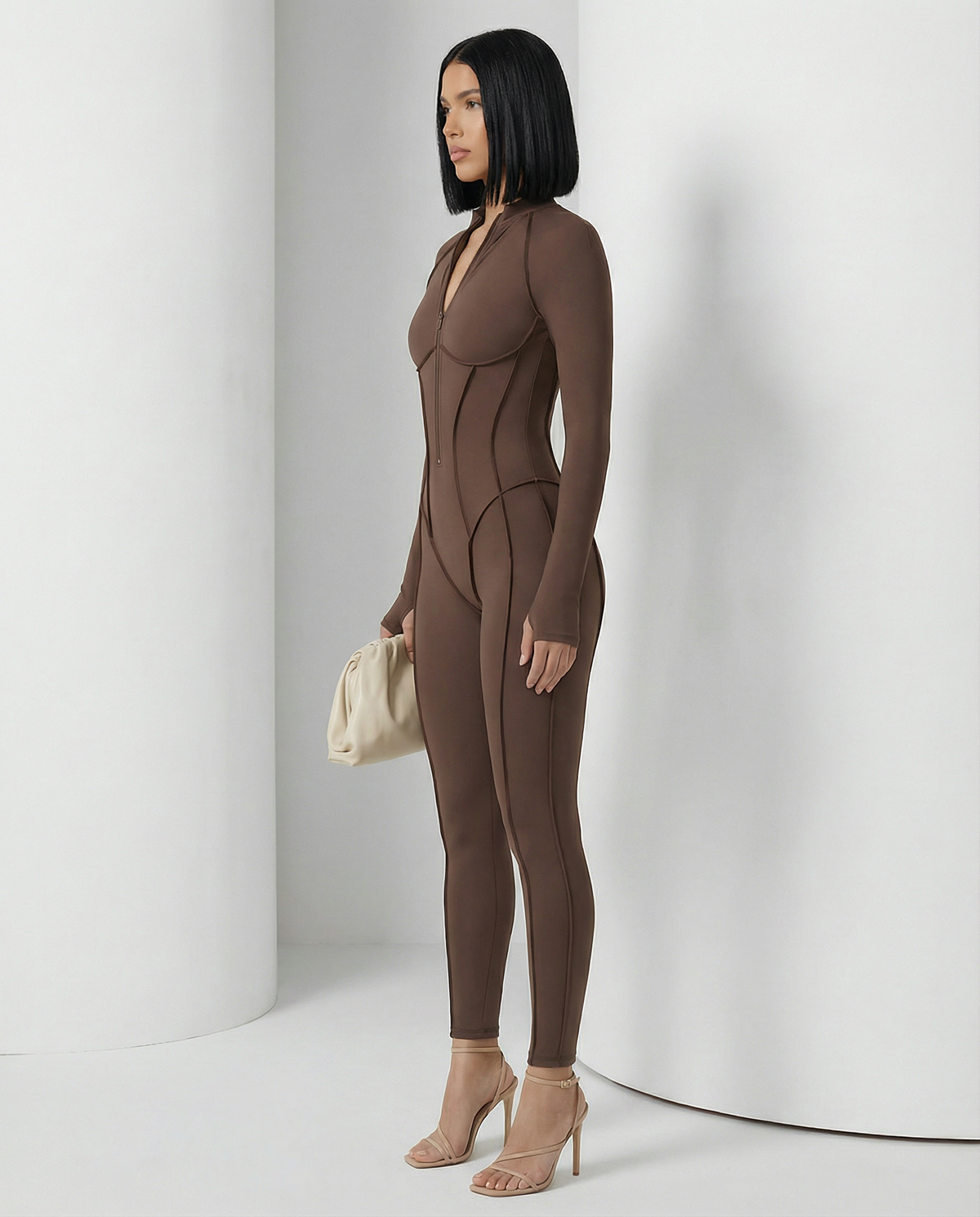 Bitter chocolate Selene Sculpt Jumpsuit in a three-quarter turn, contour seams from bust to ankle
