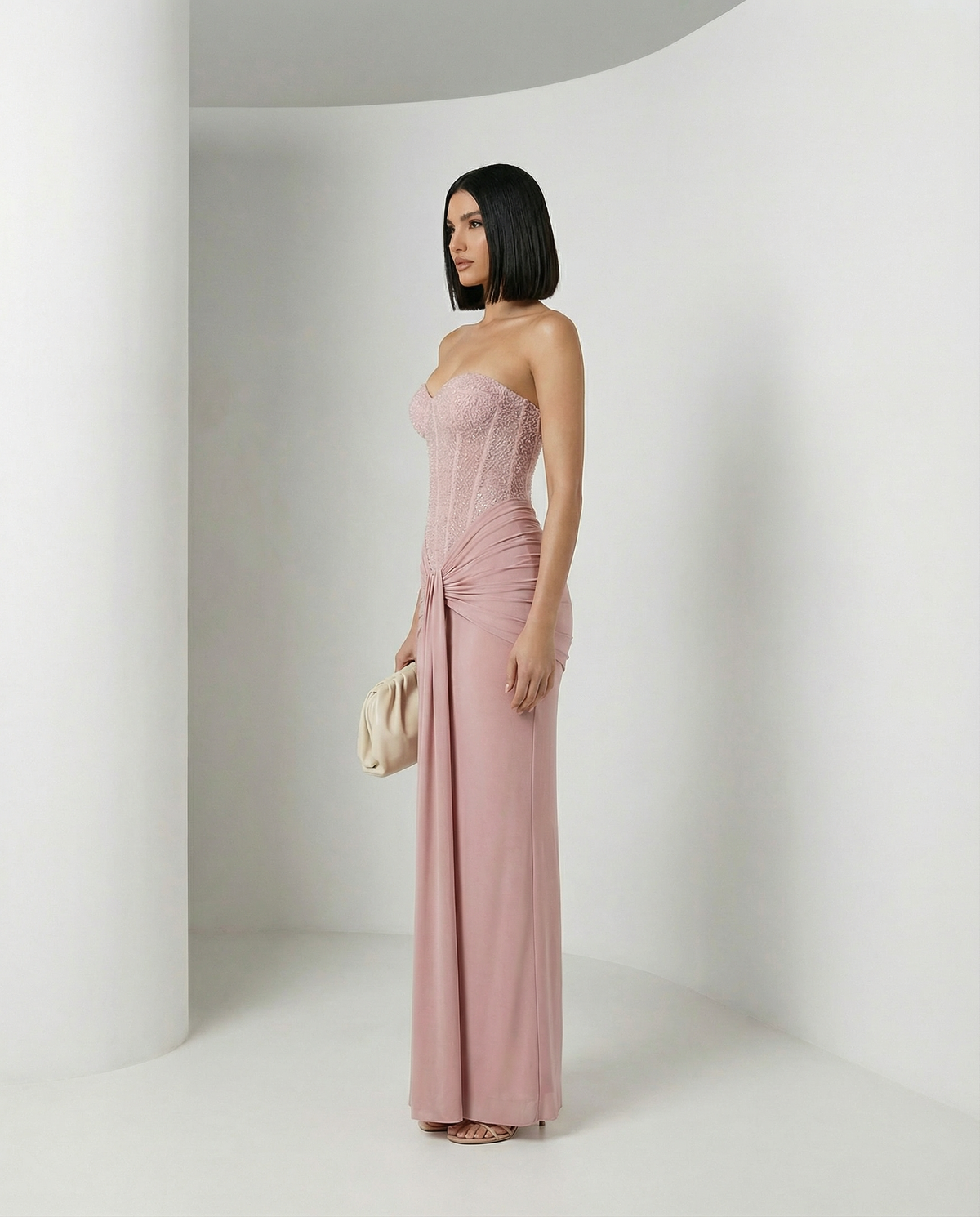 Rose gold Siren Dress in dusty pink, three-quarter view with corset bodice and long drape panel
