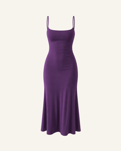 The Siv midi slip dress in purple, narrow straps, straight neckline and a fluted hem, alone on a bone background