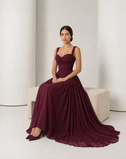 Model seated in the Solveig burgundy gown, skirt spread to show its fullness