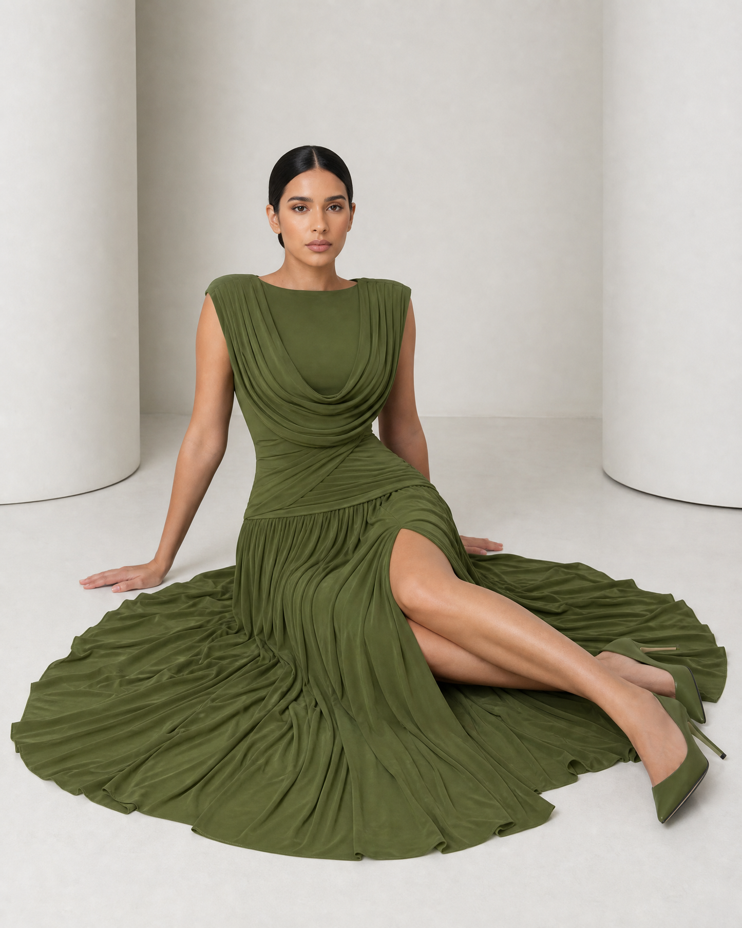 Model seated on the floor in the olive Thora gown, the gathered skirt pooled wide around her