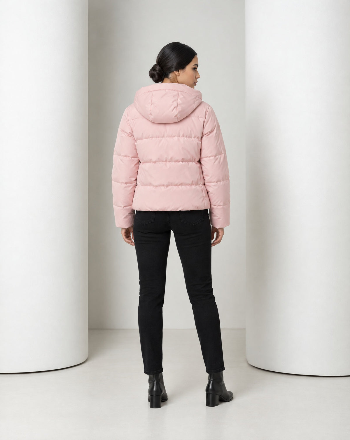 Back view of the Tove puffer in pink, hood down over the quilted back at the hip