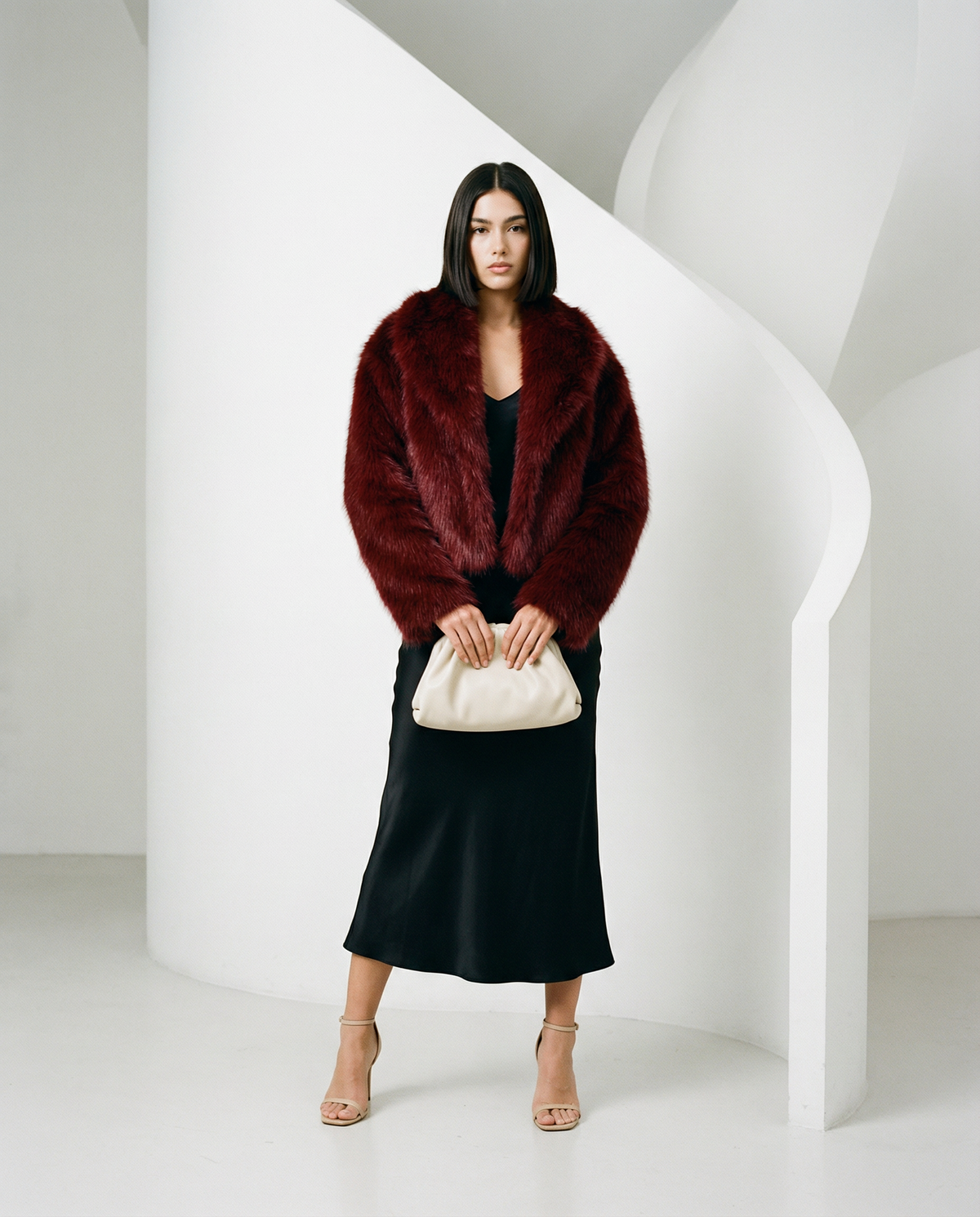 Burgundy Vera faux-fur jacket worn open over a black slip midi dress, full length front view