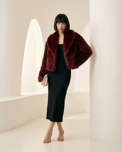 Vera faux-fur jacket in deep burgundy with shawl collar, model standing against a curved wall