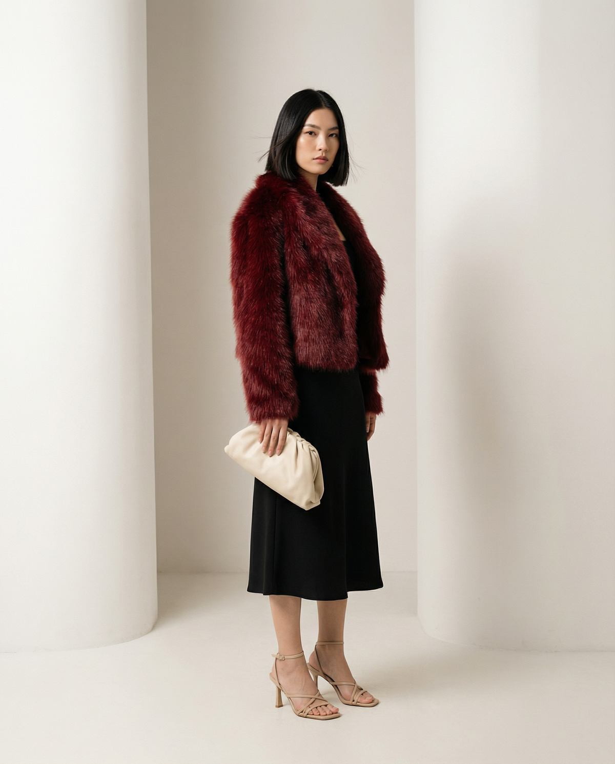 Burgundy cropped faux-fur jacket seen from a three-quarter side, hem cut just below the waist