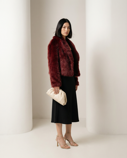Burgundy cropped faux-fur jacket seen from a three-quarter side, hem cut just below the waist