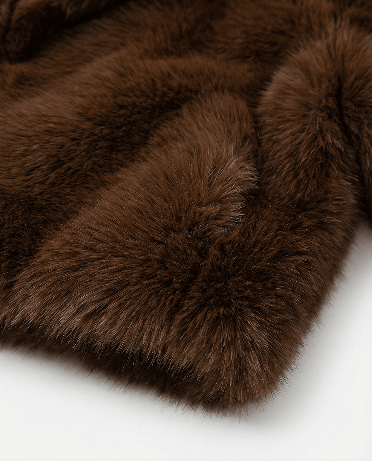 Close detail of the dense cocoa brown faux fur, showing pile texture and the swept sleeve seam