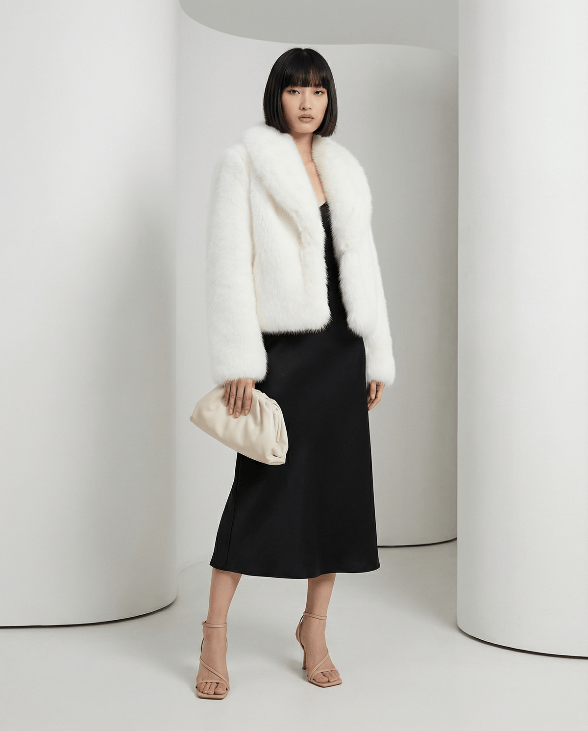 Ivory faux-fur jacket fastened at the front, hand resting on a cream pouch clutch, full length