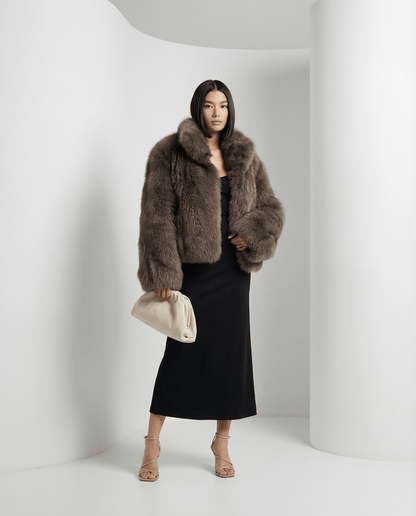 Taupe Vesper faux-fur jacket, cropped with a shawl collar, worn over a black midi skirt