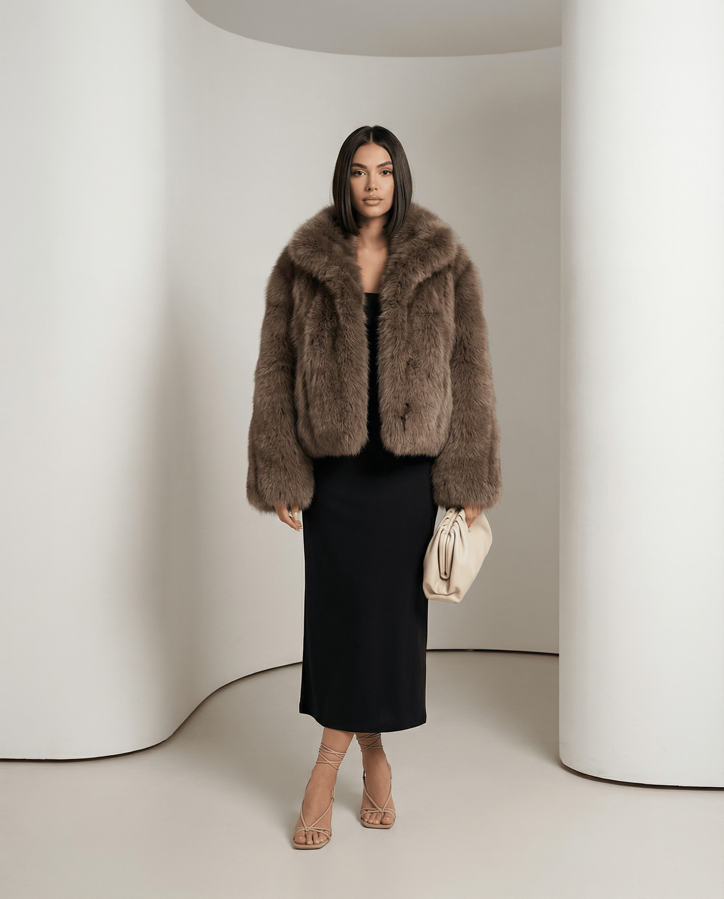 Vesper faux-fur jacket in warm taupe worn open over a black column dress, full-length front view